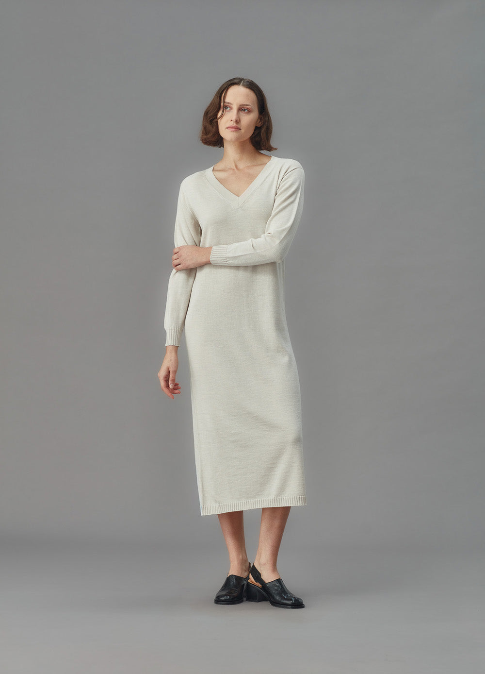 Woman wearing a light gray dress against a plain background