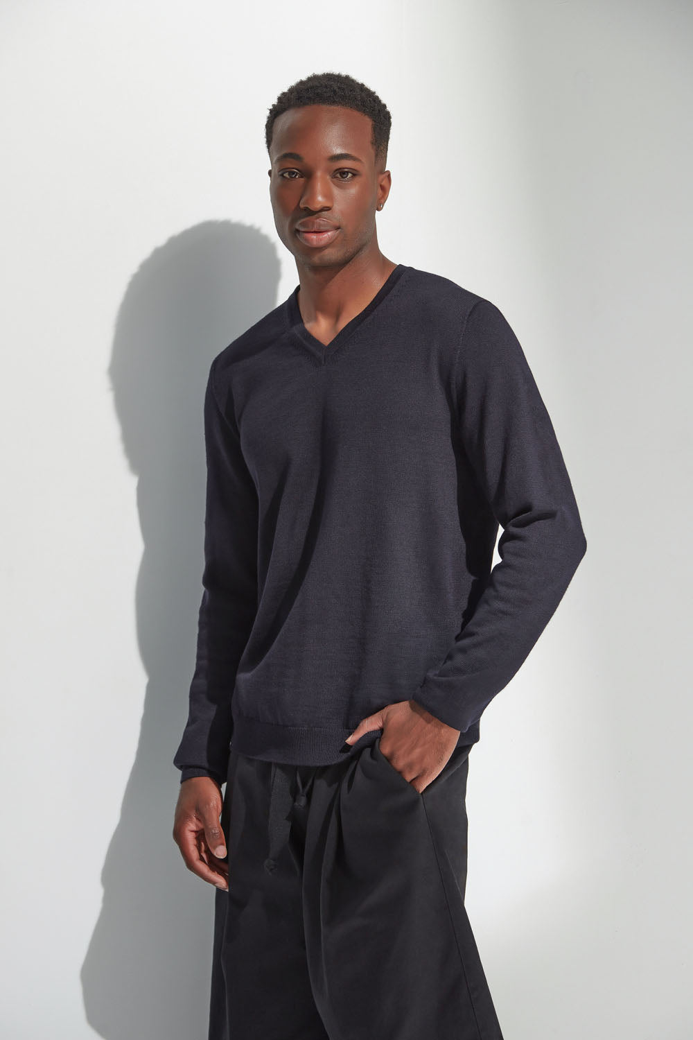 Man wearing a dark navy long-sleeve shirt and black pants against a white background