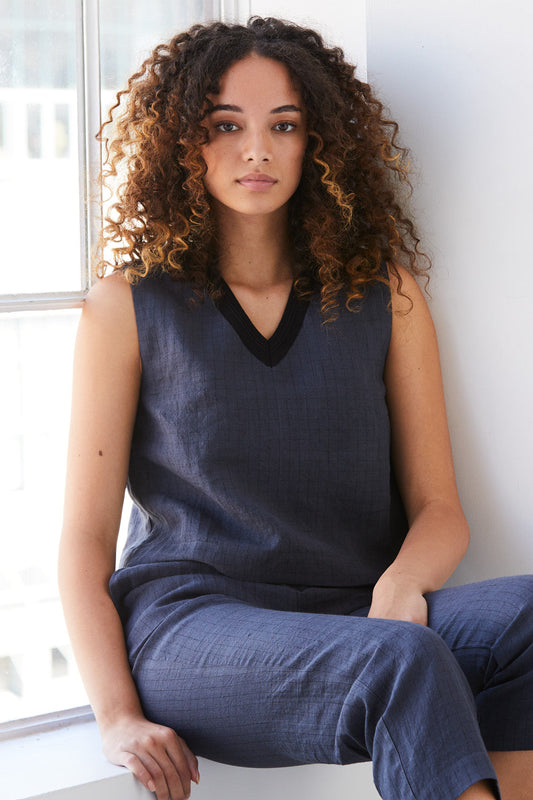 A woman sitting wearing a charcoal-coloured Standard Issue Grid Linen Top.