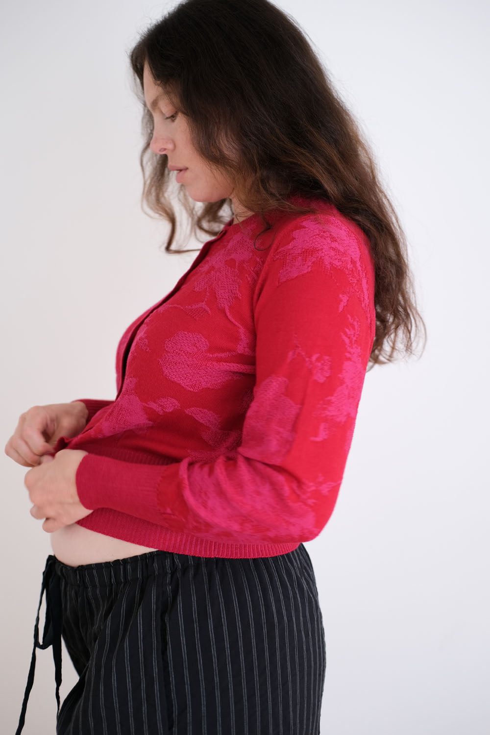 Woman wearing a red floral-patterned cardigan on a white background