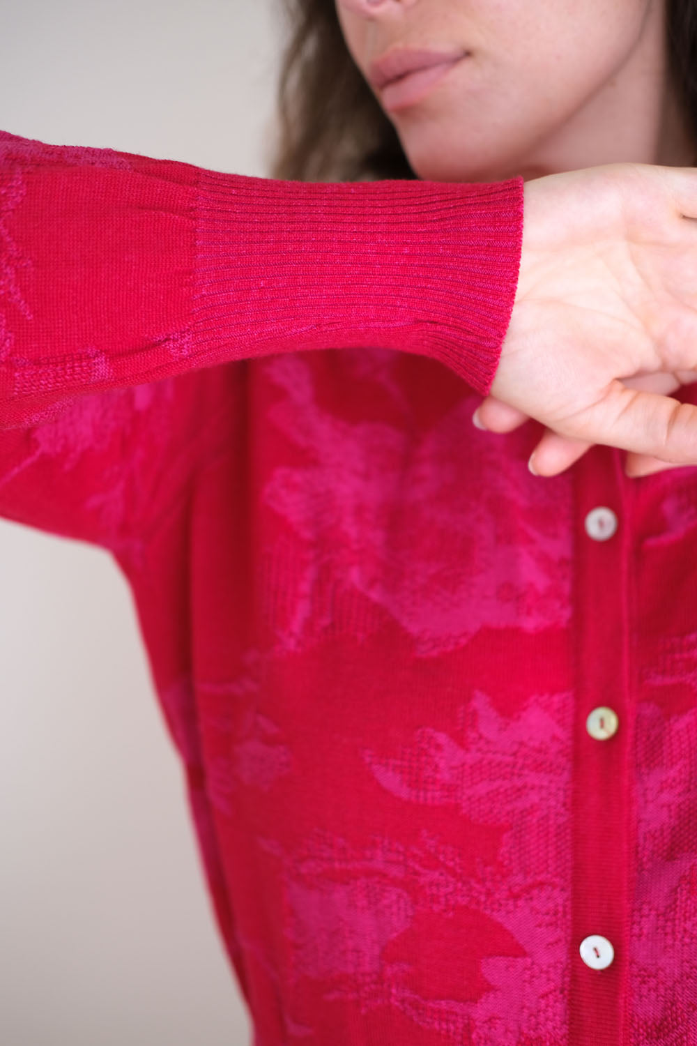 Woman wearing a red patterned cardigan against a white background
