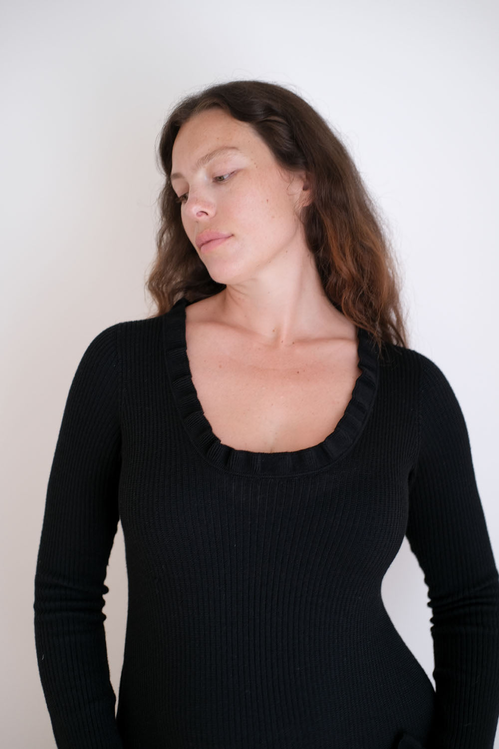 Woman wearing a black long-sleeve dress against a plain background