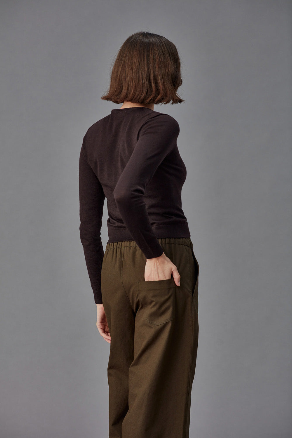 Woman wearing a brown merino cardigan against a gray background