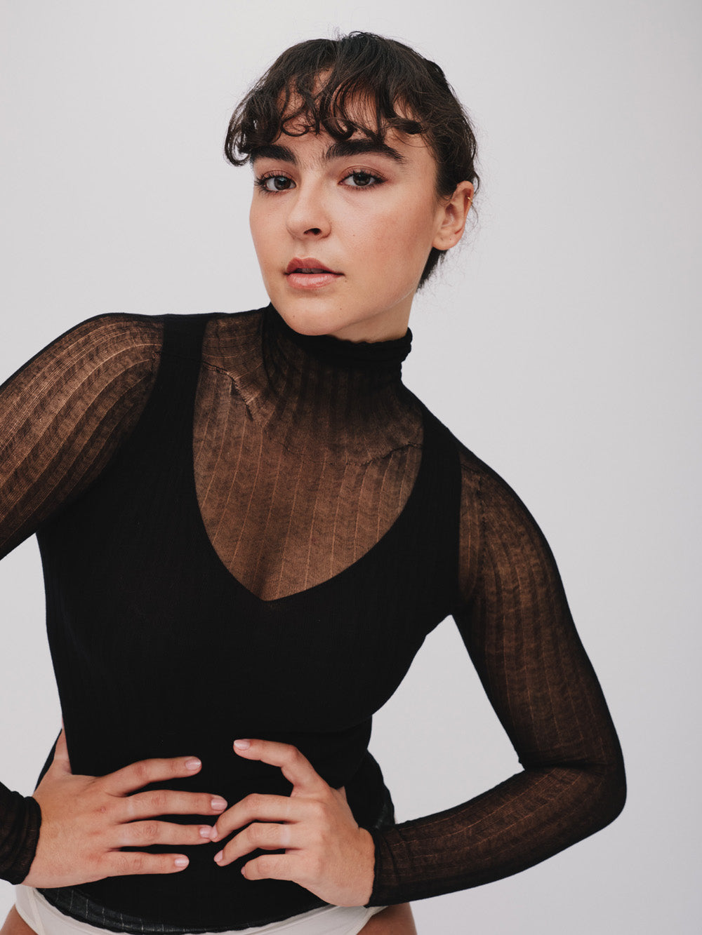 Woman wearing a sheer black tulle top against a plain background