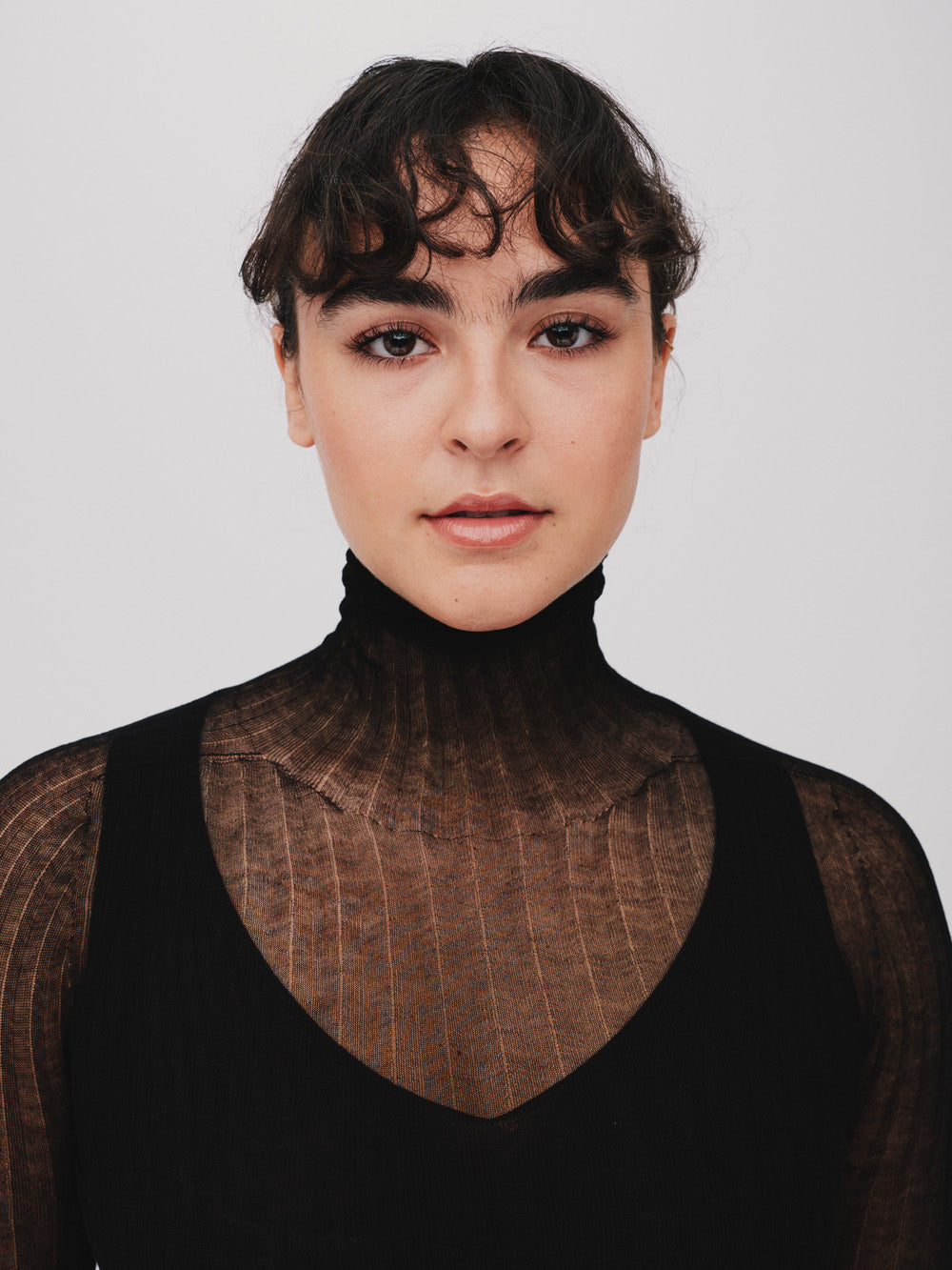 Woman wearing a sheer black tulle top against a plain background