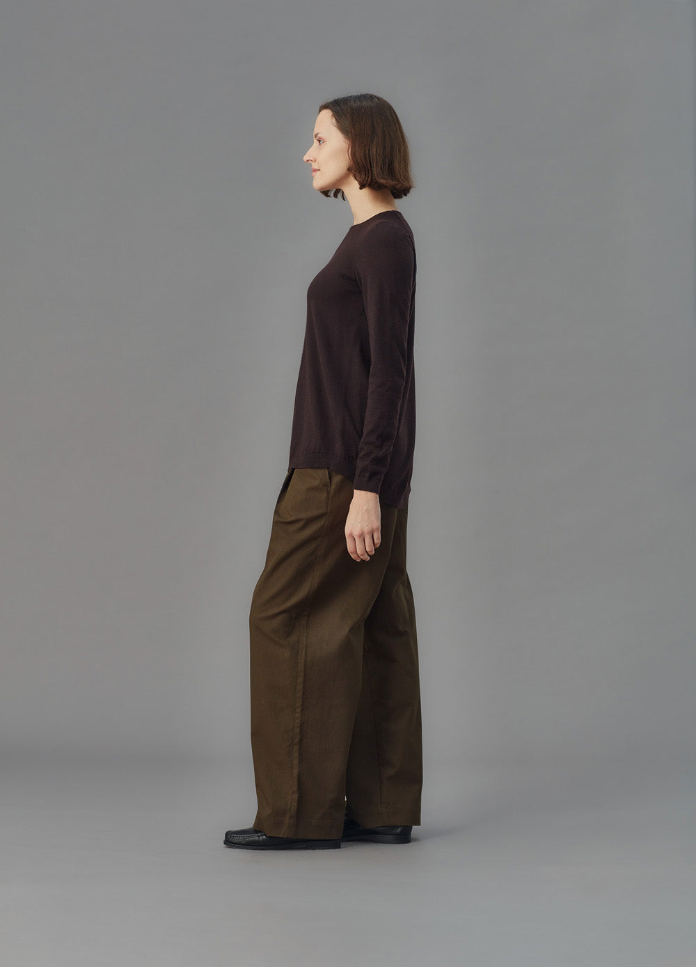 Person wearing a brown sweater and wide-leg pants on a gray background