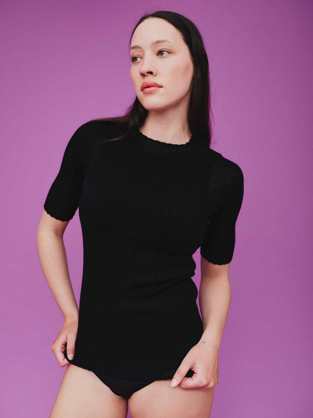 Woman wearing a black merino tulle top against a purple background