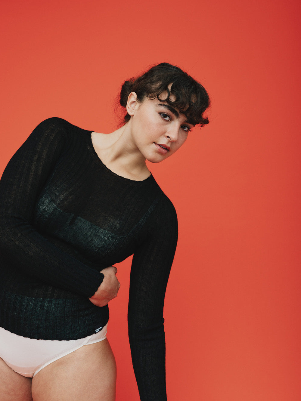 Woman wearing a black ribbed merino tulle on a orange background