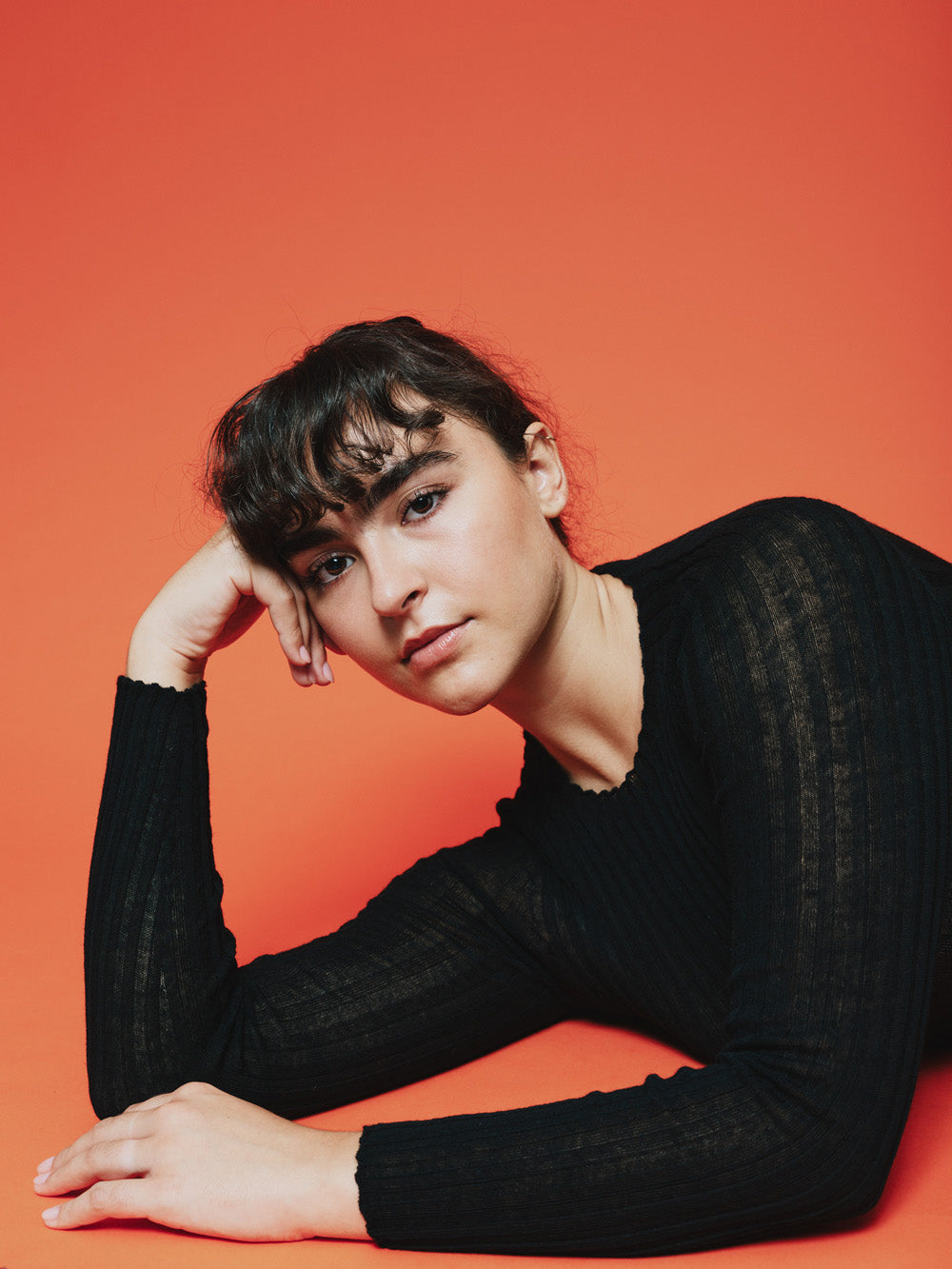 Woman wearing a black ribbed merino tulle on a orange background