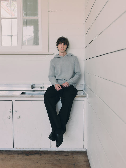 Person sitting on a kitchen counter wearing a light blue knit hoodie and dark pants.