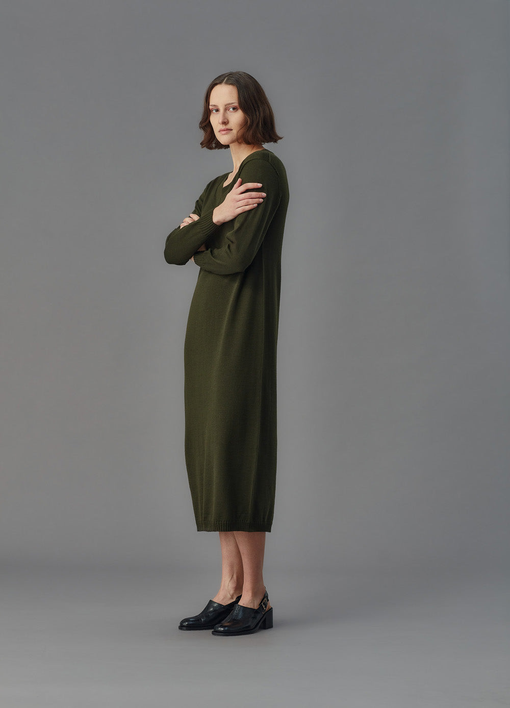 Woman wearing a green dress standing against a gray background