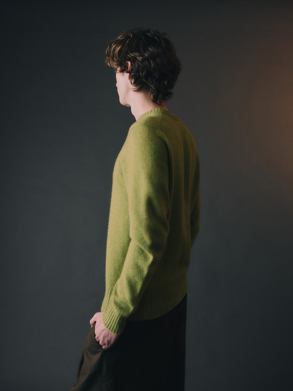 Person wearing a green sweater against a dark background