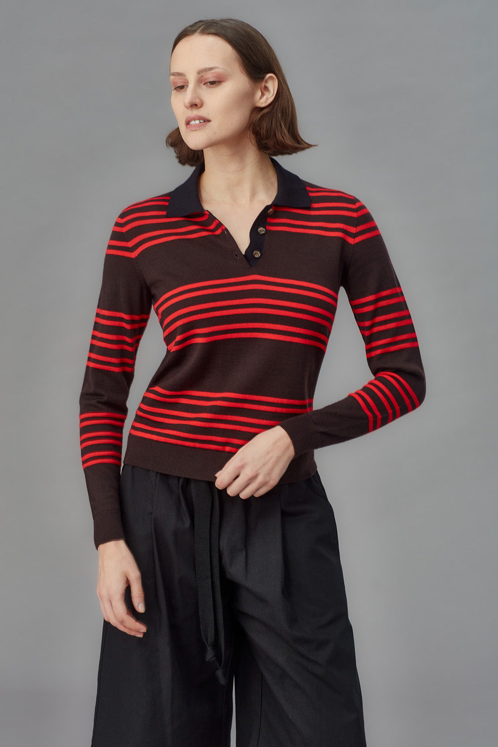 Woman wearing a brown and red striped sweater against a gray background