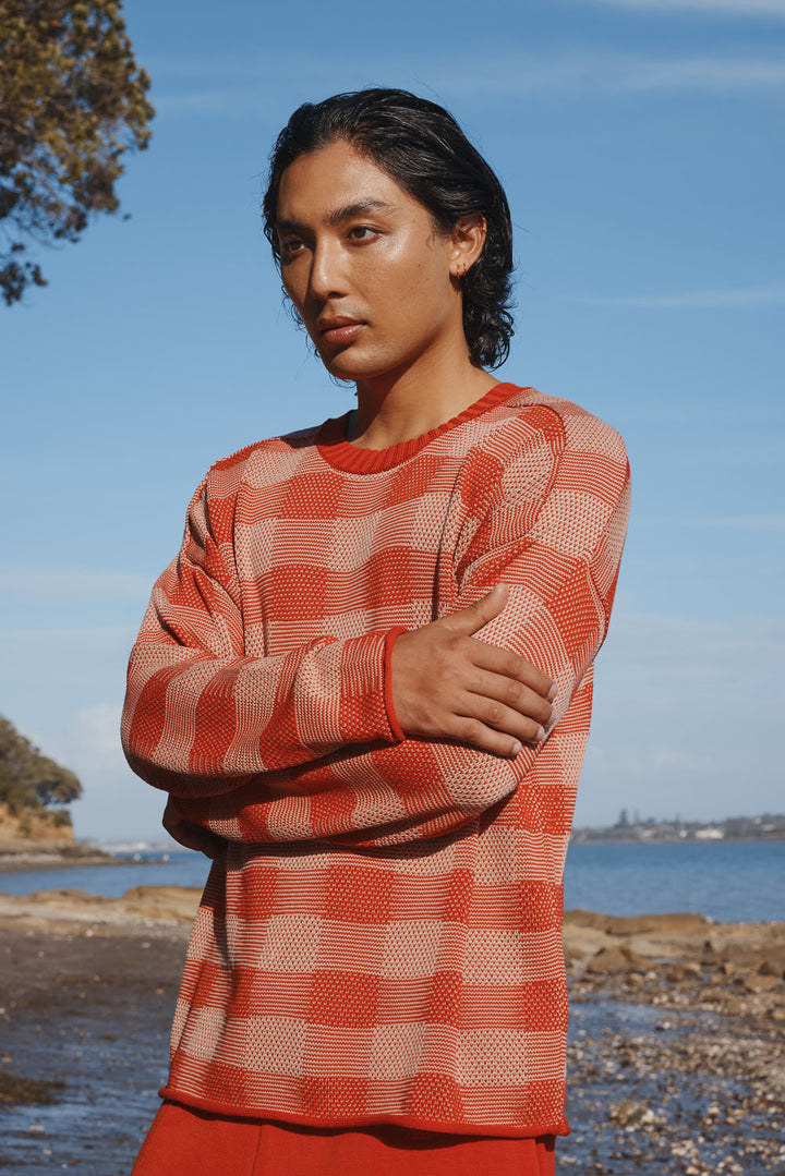 Man wearing a red and white checkered sweater by a body of water