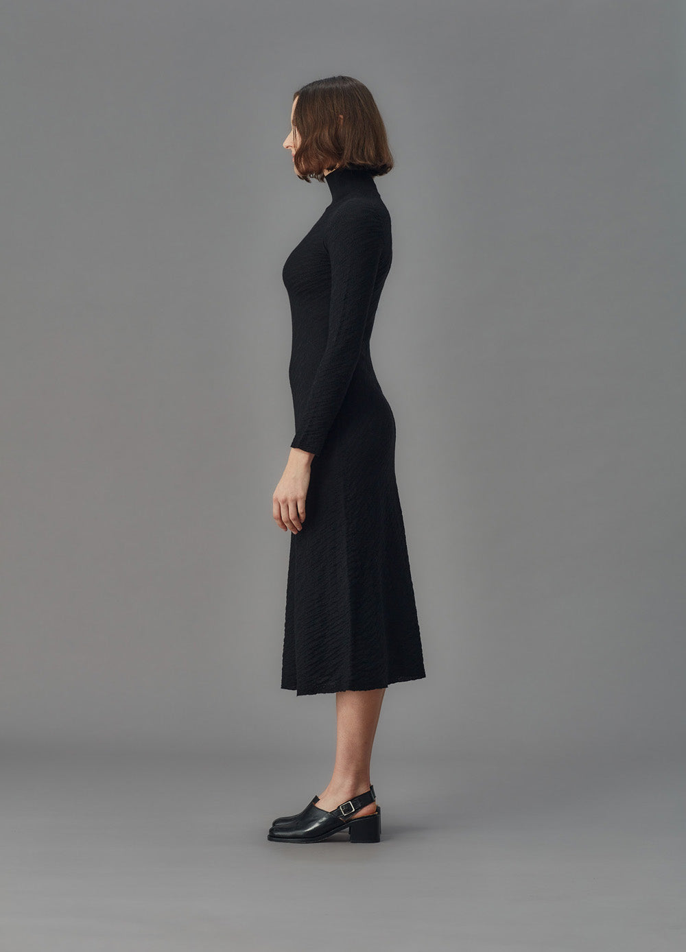 Woman wearing a black dress against a gray background