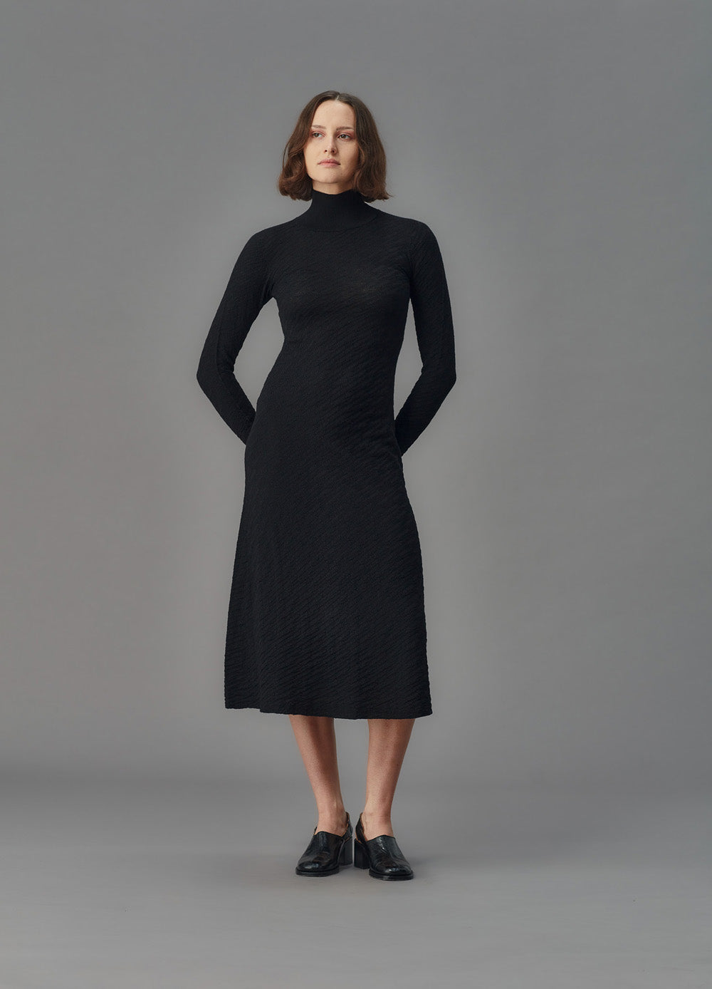 Woman wearing a black dress against a gray background