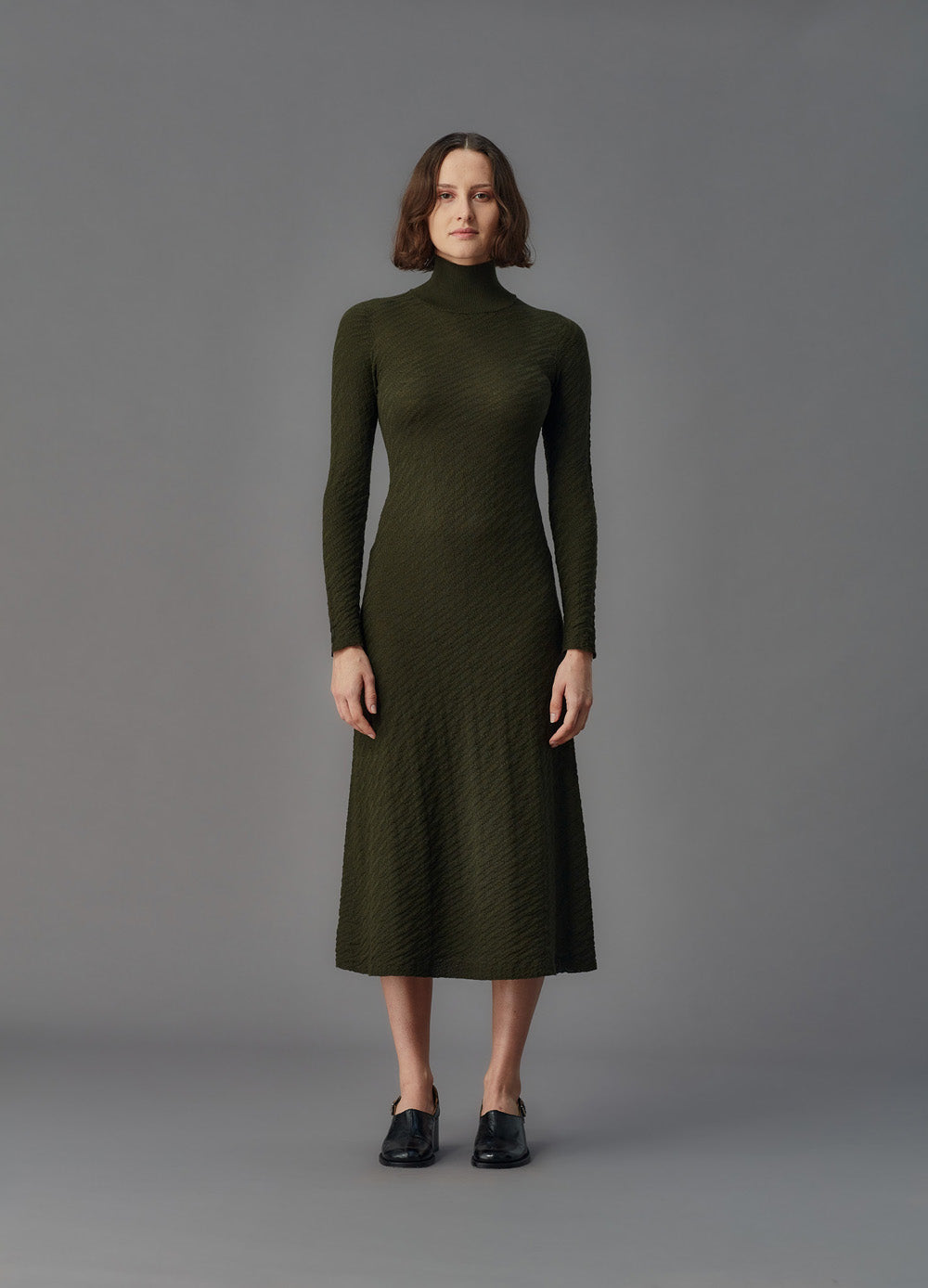 Woman wearing a green dress against a gray background