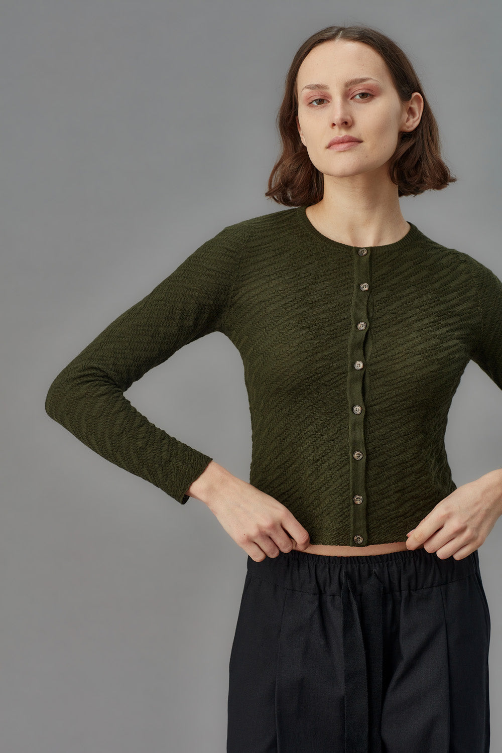 Woman wearing a green cardigan against a gray background