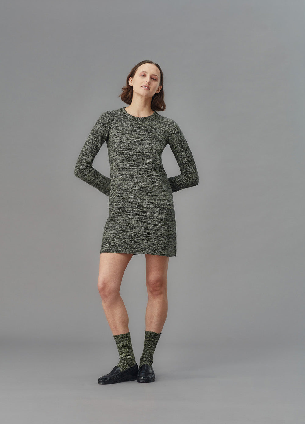 Woman wearing a green knit dress on a gray background
