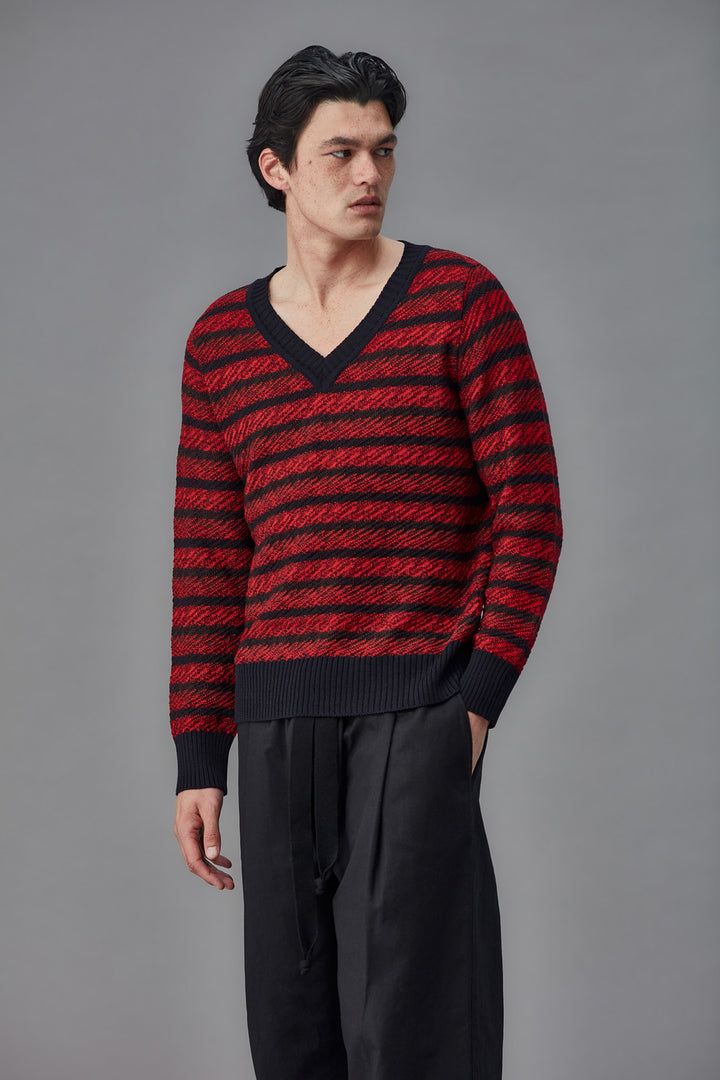 Man wearing a red and black striped sweater against a gray background