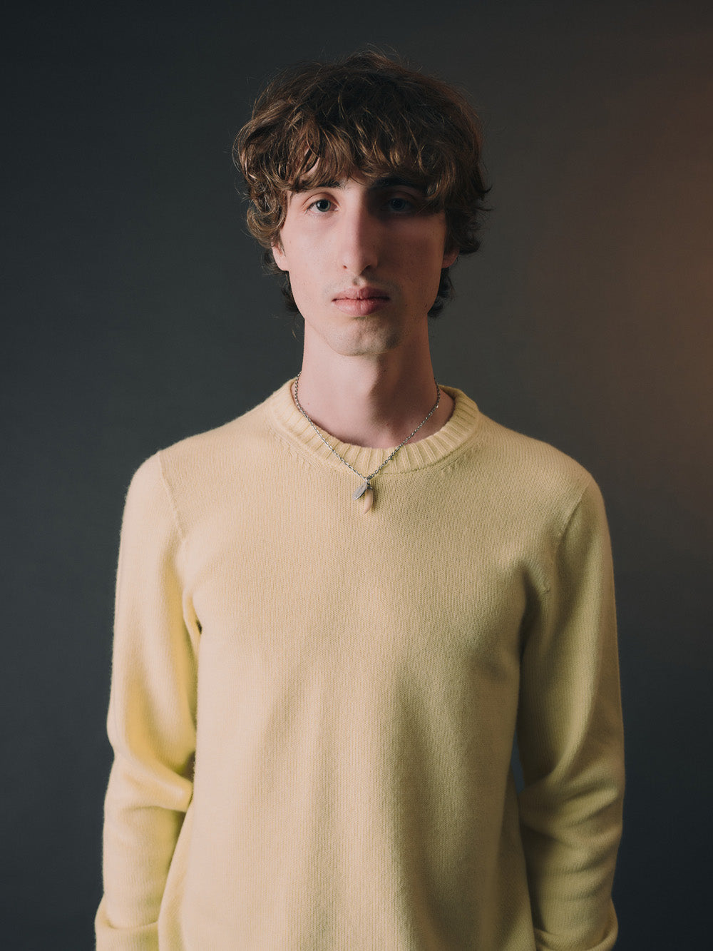 Man wearing a light yellow cashmere sweater against a gradient background