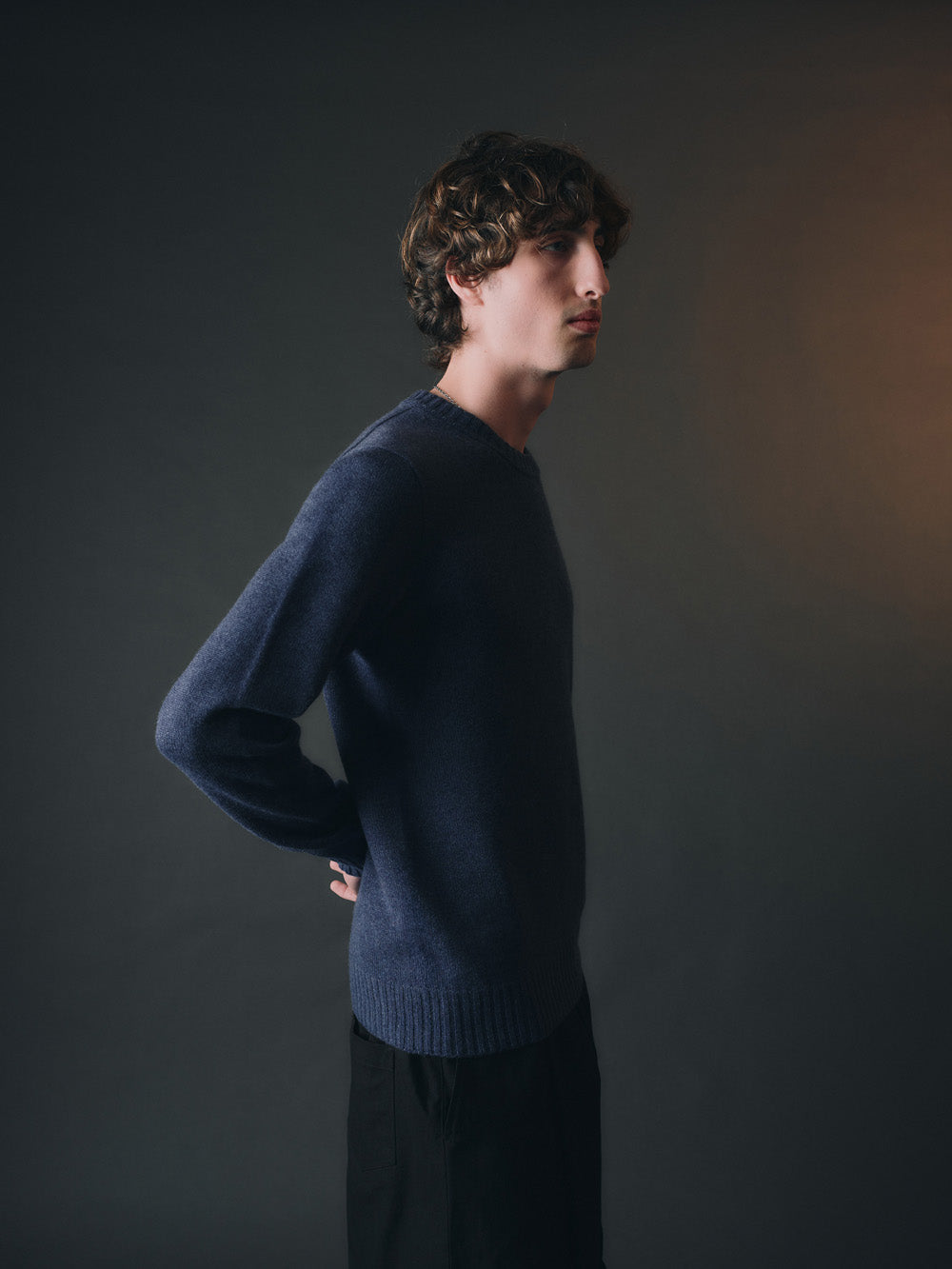 Man wearing a dark blue cashmere sweater against a dark background