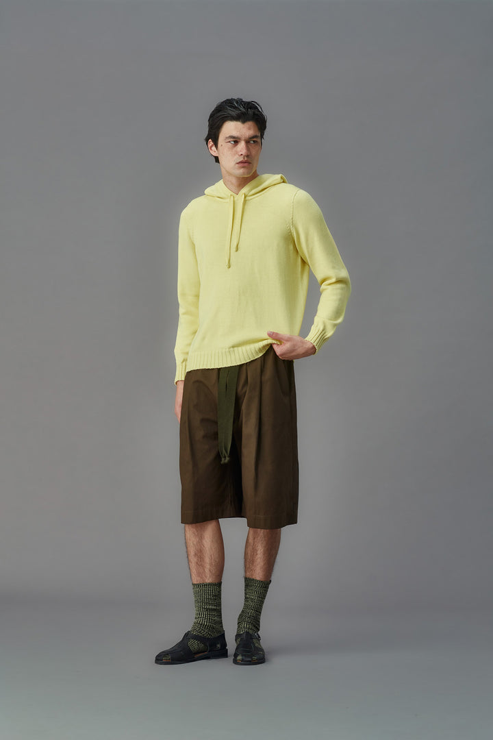 Person wearing a light yellow hoodie and brown shorts on a gray background