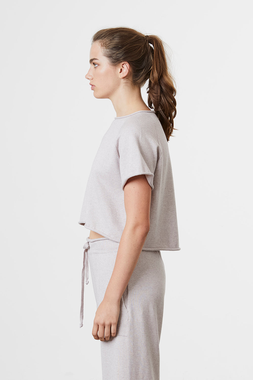 Woman facing sideways wearing Standard Issue Balance Wide Tee in Shell colour.