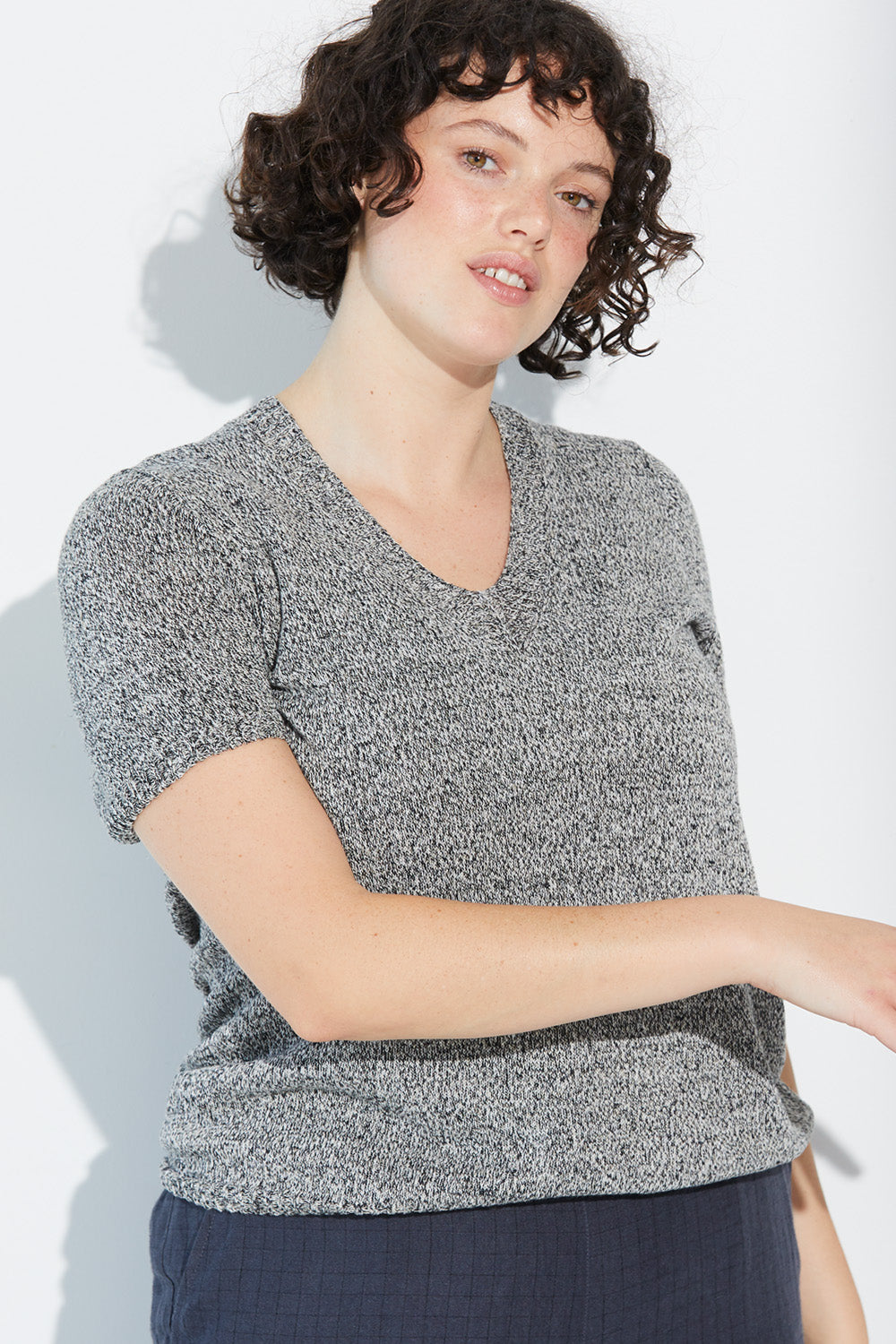 A woman standing wearing a twist-coloured Standard Issue Linen Tee.