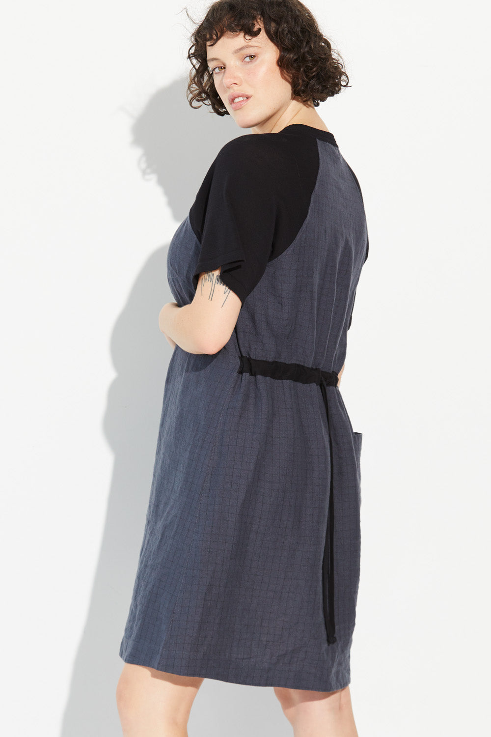 A woman looking over shoulder wearing a charcoal-coloured Standard Issue Grid Linen Dress.