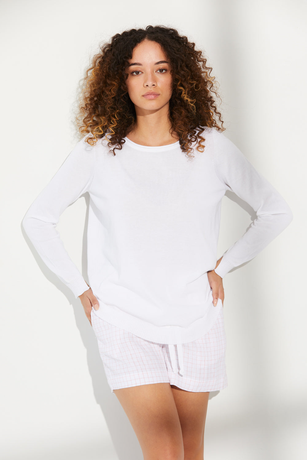 A woman standing wearing a white Standard Issue Cotton Curved Jumper.