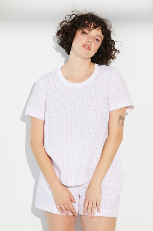 A woman standing wearing a white Standard Issue Grid Linen Tee.