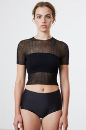 A woman standing wearing a black Standard Issue Cotton Tulle Crop Tee.